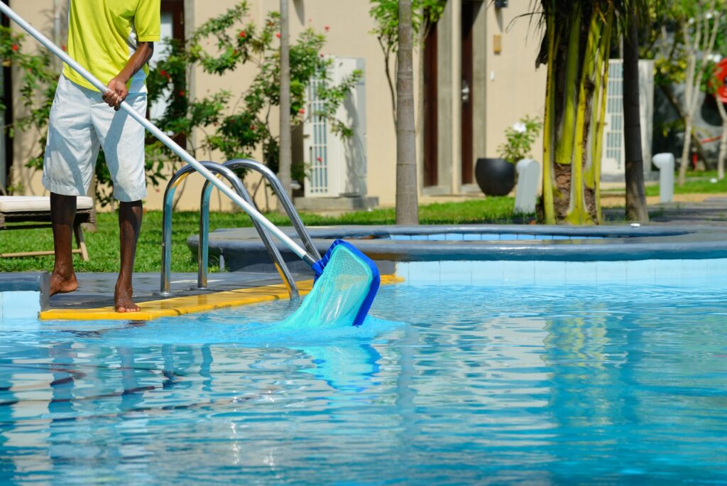 A man cleans the pool - swimming pool contractors